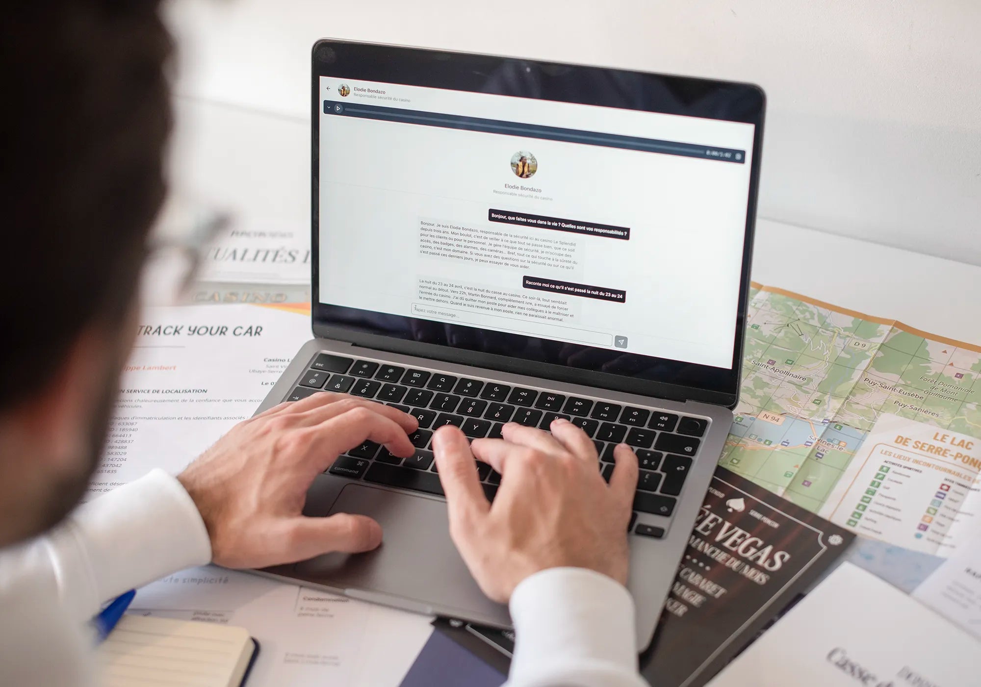 Un enquêteur Deep Detective est entrain d’interroger un témoin de l’affaire sur ordinateur, carte du lac de Serre-Ponçon à côté, dans une enquête immersive à la maison.